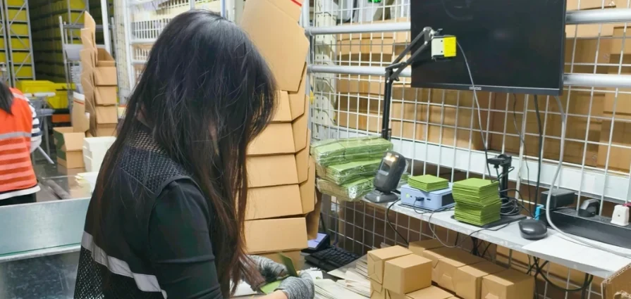A team member checking cartons beside a dispatch terminal