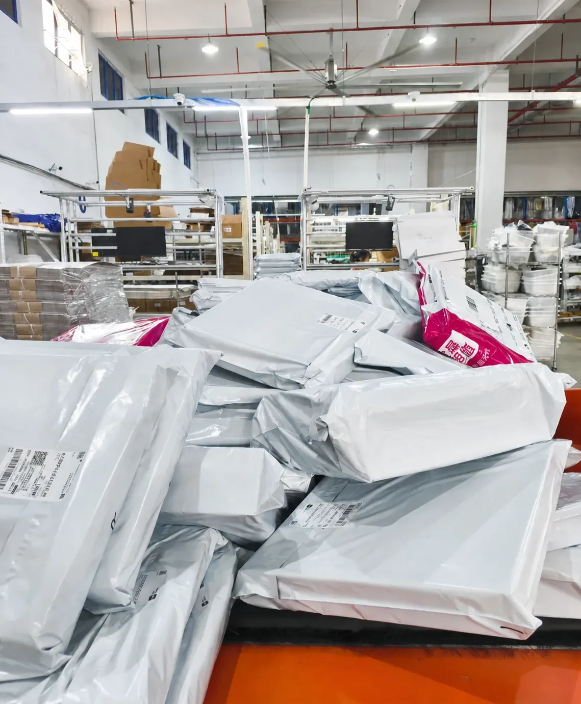 Packed mailing bags gathered beside warehouse workstations
