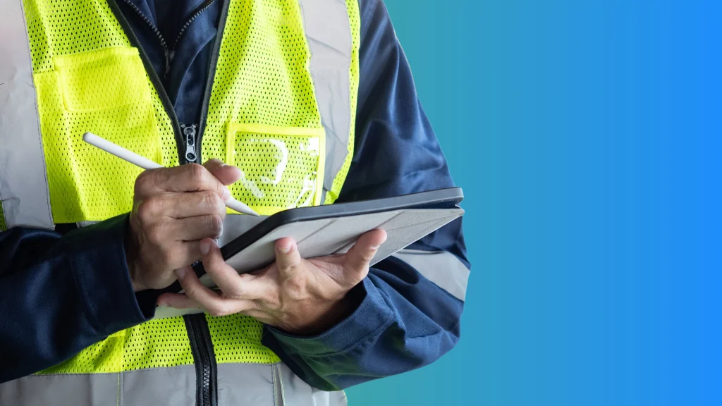 A worker in a high-visibility yellow vest using a tablet and stylus to conduct a quality control inspection, with a blue background.